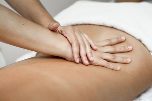 Young woman receiving a back massage in a spa center. Female patient is receiving treatment by professional therapist.