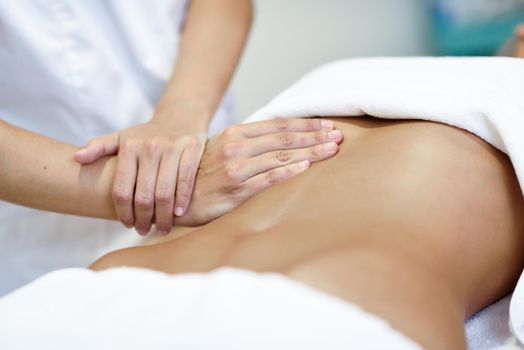 Hands massaging female abdomen.Therapist applying pressure on belly. Woman receiving massage at spa salon