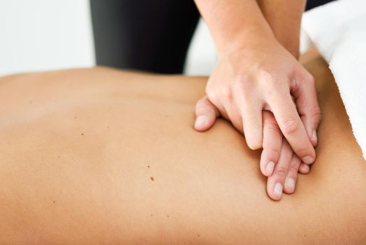 Young female receiving a relaxing back massage in a spa center. Brunette woman patient is receiving treatment by professional therapist.