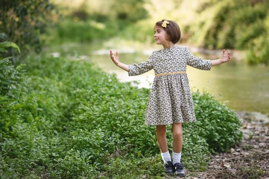 Little beautiful girl in nature stream wearing beautiful dress