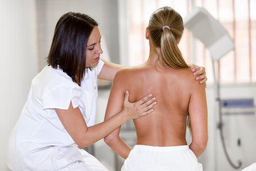 female physiotherapist inspecting her patient. Medical check at the shoulder in a physiotherapy center.