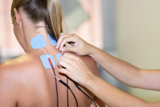 Electro stimulation in physical therapy to a young woman. Medical check at the shoulder in a physiotherapy center.
