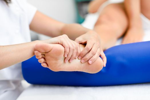 Medical massage at the foot in a physiotherapy center. Female physiotherapist inspecting her patient.