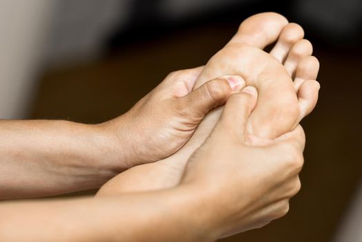 Medical massage at the foot in a physiotherapy center. Female physiotherapist inspecting her patient.