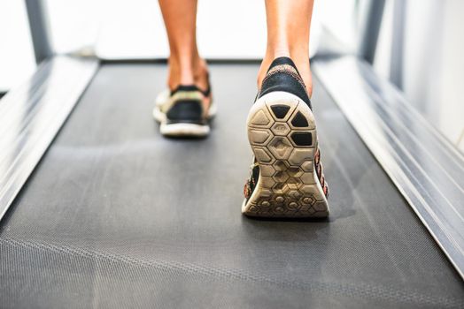 Male muscular feet in sneakers running on the treadmill at the gym. Concept for fitness, exercising and healthy lifestyle.