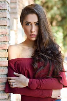 Woman with beauty long brown hair posing outdoors. Girl wearing casual clothes in urban background.