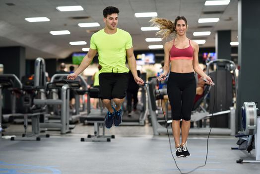 Handsome man and beautiful sporty woman workout with jumping rope in crossfit gym