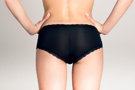 Female ass wearing black panties, white background