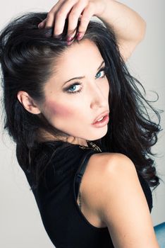 Brunette woman with blue eyes wearing sweater and blue jeans on white background. Studio shoot