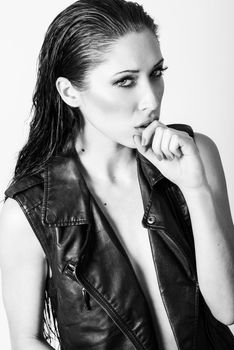 Brunette woman with blue eyes wearing black leather jacket and panties on white background. Studio shoot
