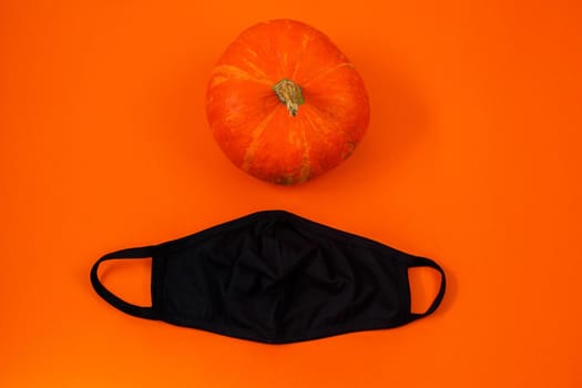 Halloween 2020 concept. Pumpkin and protective face mask on orange background.