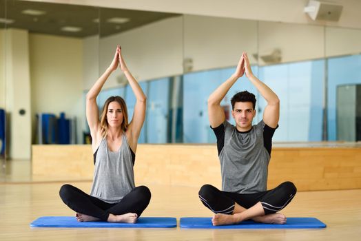 Young woman and man practicing yoga indoors. Two people doing exercises.