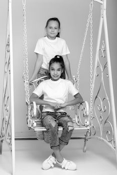 Two beautiful little girls near the swing. The concept of tenderness and beauty.