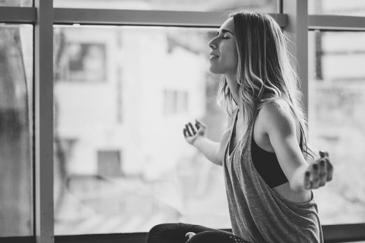 Young beautiful woman meditating in the lotus position in gym. Girl wearing sportswear clothes.