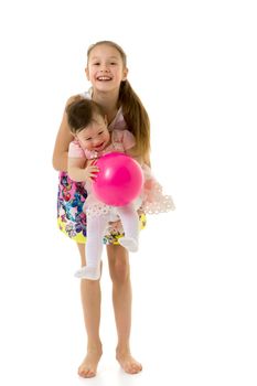 Cute Happy Girls Laughing and Playing Together with Pink Balloon, Teen Girl Holding Cute Toddler Sister on Her Hands, Two Adorable Happy Children Having Fun on Isolated on White Background