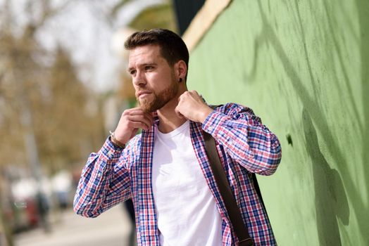 Attractive young man standing in urban background. Guy wearing casual clothes. Lifestyle concept.