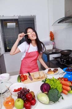 Cheerful woman is covering her eye with spoon in kitchen room at home