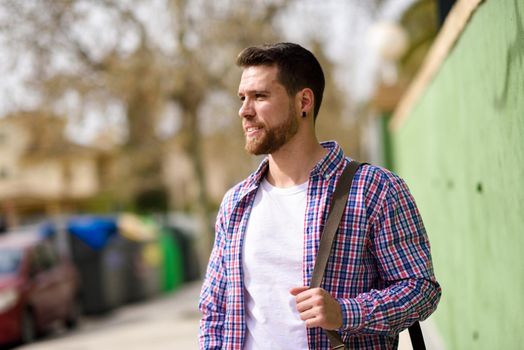 Attractive young man standing in urban background. Guy looking away wearing casual clothes. Lifestyle concept.