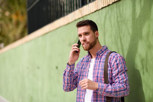 Young man talking with his smart phone in urban background. Guy wearing casual clothes. Lifestyle concept.