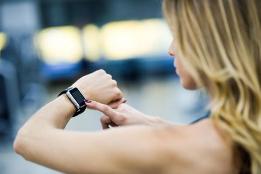 Young woman using smartwatch at the gym. Caucasian female working out.