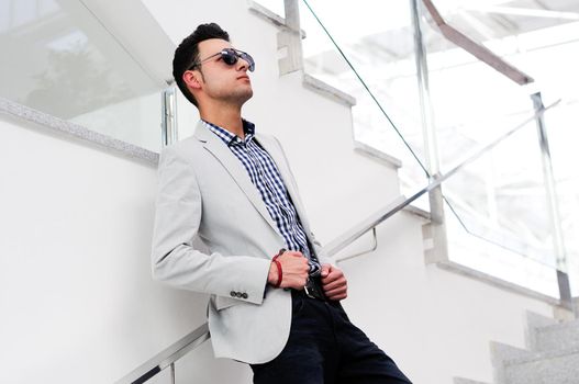 Portrait of a young handsome man, model of fashion, wearing tinted sunglasses