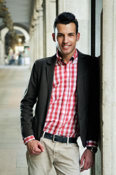 Portrait of a young handsome man, model of fashion, wearing jacket and shirt in urban background