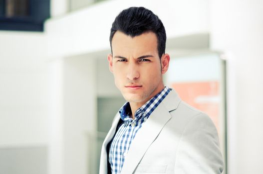 Portrait of a young handsome man, model of fashion, wearing jacket and shirt in urban background