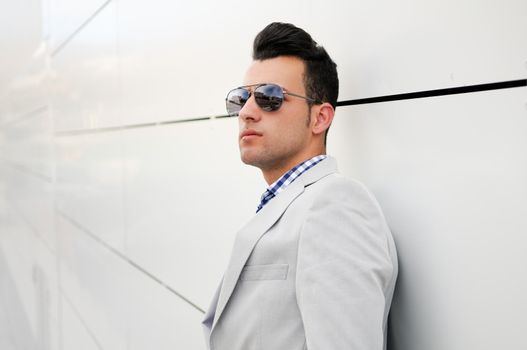 Portrait of a young handsome man, model of fashion, wearing tinted sunglasses