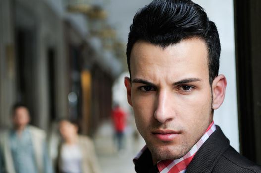 Close-up portrait of a young handsome man, model of fashion, wearing jacket and shirt in urban background