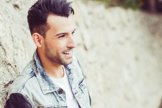 Portrait of a young handsome man, model of fashion, with modern hairstyle in urban background, smiling