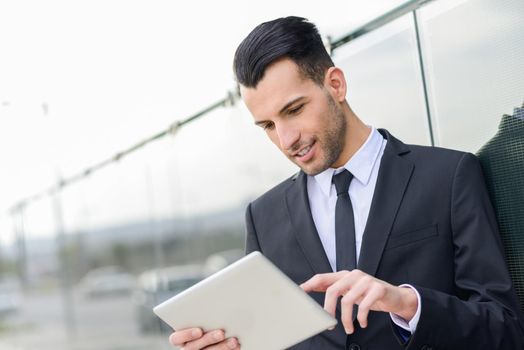 Portrait of attractive young businessman smiling with a tablet computer in an office building