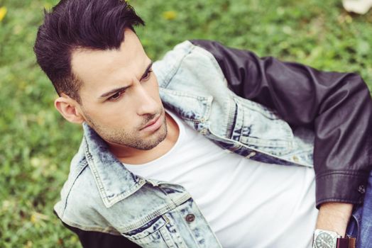 Portrait of a young handsome man, model of fashion, with modern hairstyle in urban background