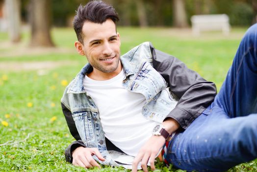 Portrait of a young handsome man, model of fashion, with modern hairstyle smiling in urban background