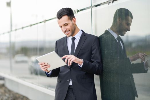 Portrait of attractive young businessman smiling with a tablet computer in an office building