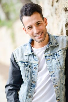 Portrait of a young handsome man, model of fashion, with modern hairstyle smiling in urban background