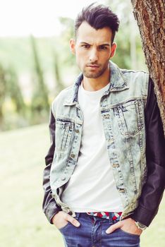 Portrait of a young handsome man, model of fashion, with modern hairstyle in urban background