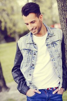 Portrait of a young handsome man, model of fashion, with modern hairstyle smiling in urban background