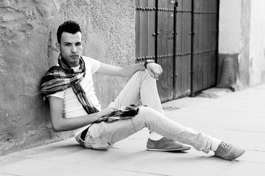 Portrait of a young attractive man sitting on the floor of the street