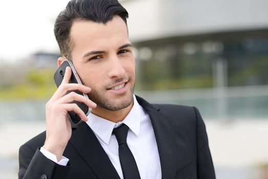 Portrait of an attractive young businessman smiling on the phone in an office building