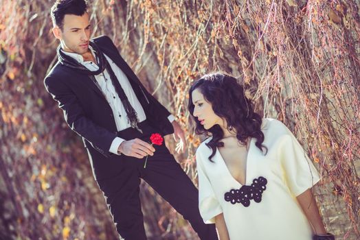 Portrait of a young man giving red carnation to his girl