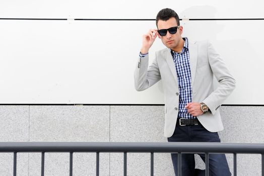 Portrait of a young handsome man, model of fashion, wearing tinted sunglasses