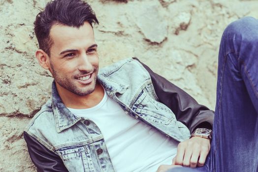 Portrait of a young handsome man, model of fashion, with modern hairstyle smiling in urban background