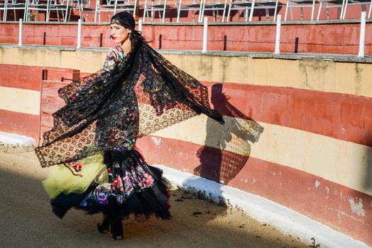 Portrait of a pretty woman, model of fashion, wearing a dress in a bullring. Spanish style