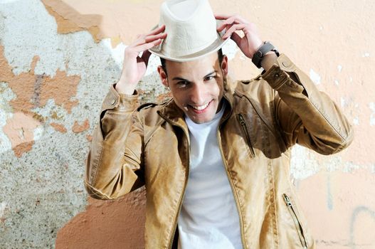 Portrait of a handsome young man smiling with a hat in urban background