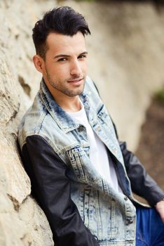 Portrait of a young handsome man, model of fashion, with modern hairstyle smiling in urban background