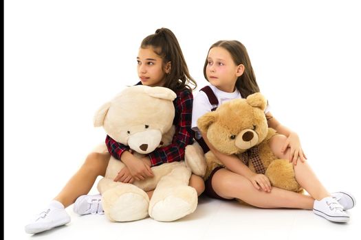 Little girl with toy. Two beautiful happy girls standing and embracing plushs toy in children room. Tenderness and beauty concept. Girls holds heap of teddy bears. Girl hugging teddybears, childhood.