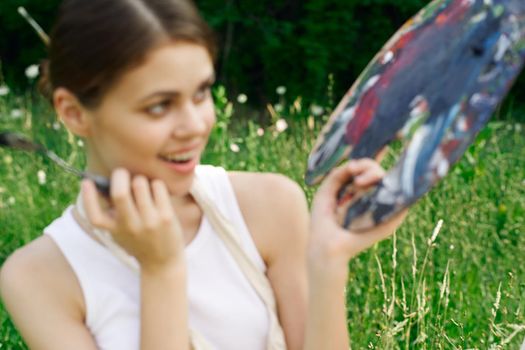 cheerful woman paints a picture palette nature landscape. High quality photo