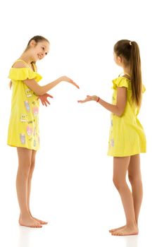 Smiling Teen Girls Standing Together Looking into the Distance, Barefoot Sisters Wearing the Same Yellow Dresses Posing at Camera, Full Length Portrait of Happy Teenagers Isolated on White Background.