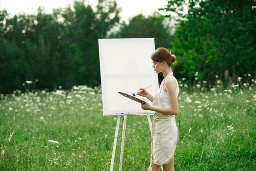 woman artist paints on easel in nature landscape. High quality photo