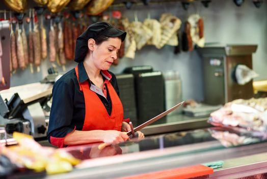 Young female butcher sharpening a knife in a butcher shop